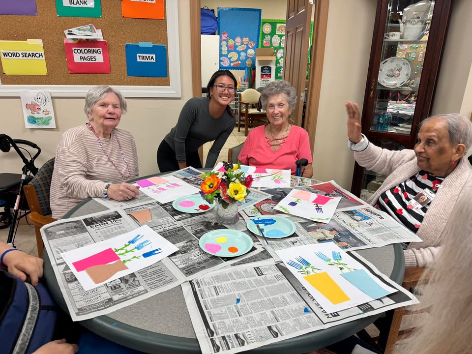 Participants and a staff member smiling during a craft activity at SarahCare